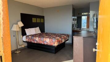 Un dormitorio con cama, lámpara de noche y cómoda.