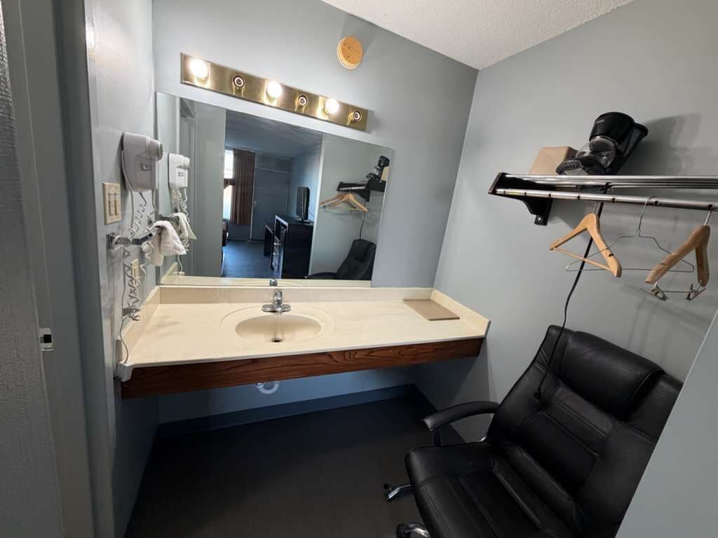 Un bagno moderno con uno specchio grande, un lavandino e una sedia nera.