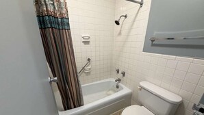 A bathroom with a bathtub, toilet, and a showerhead.