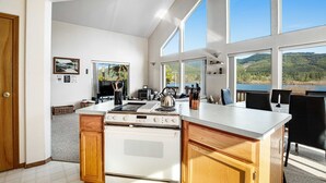Una cucina moderna con una grande isola, mobili in legno e vista su un lago.
