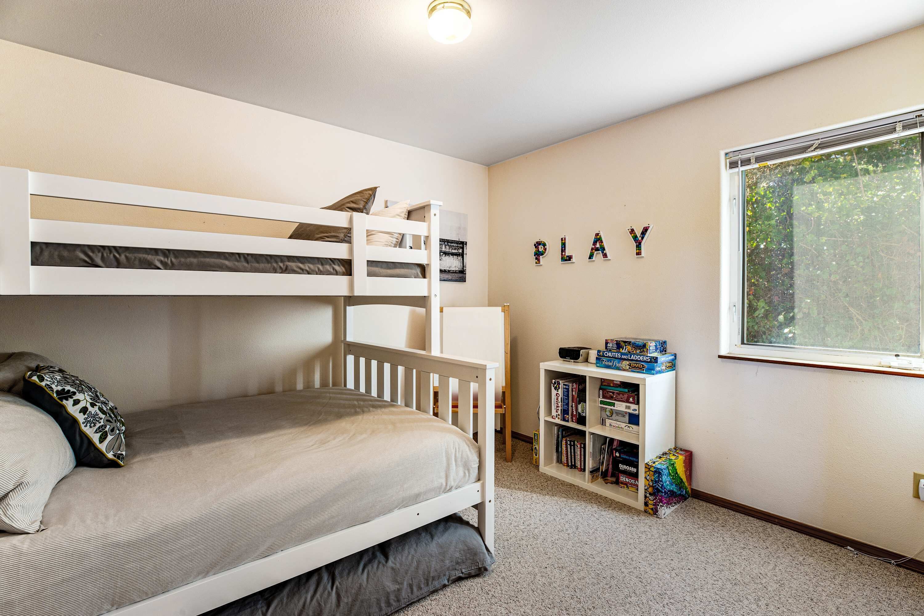 A bunk bed with a bookshelf and a window.