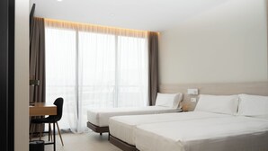 Une chambre d’hôtel avec deux lits, un bureau et une chaise.