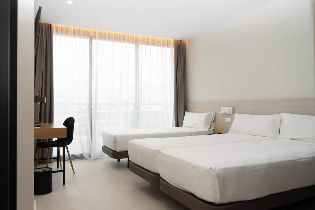 Een hotelkamer met twee bedden, een bureau en een stoel.