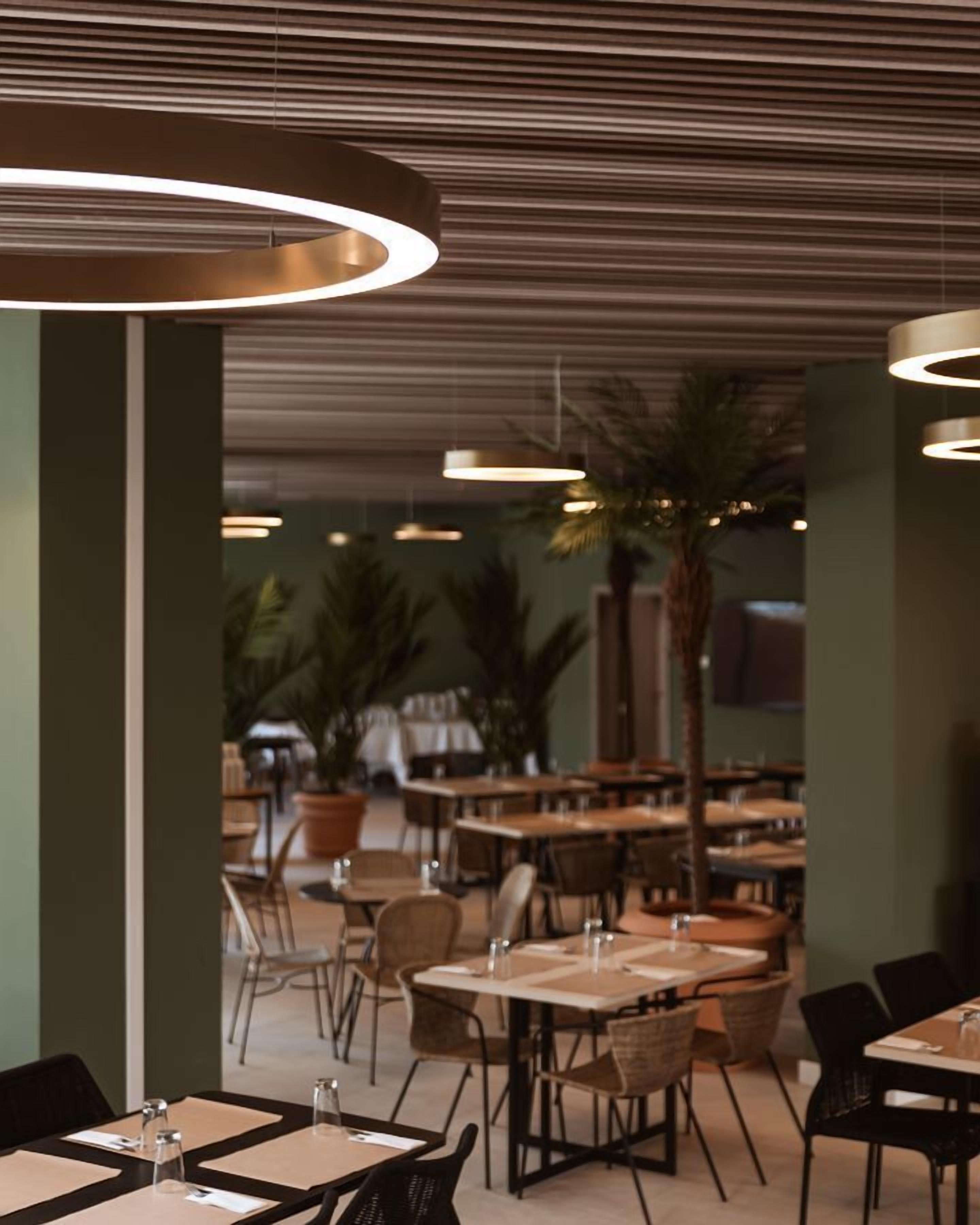 Un restaurante con mesas redondas, sillas e iluminación colgante.