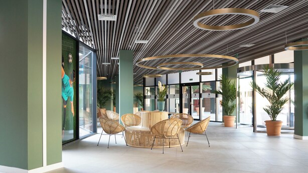 Un hall d’entrée moderne doté d’un espace salon circulaire, de grandes fenêtres et de plantes en pot.