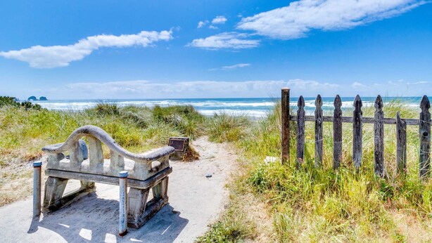 A bench and a wooden fence near a beach with a clear sky. - Modern Beach Cottage with a covered patio fire pit grill and easy beach access (Rockaway Beach)