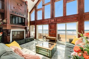 Een ruime woonkamer met een grote televisie, comfortabele zithoek en uitzicht op het strand.