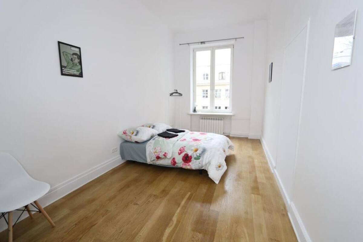 A bedroom with a bed, a chair, and a window.