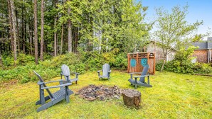 A backyard with Adirondack chairs, a fire pit, and a wooden structure.