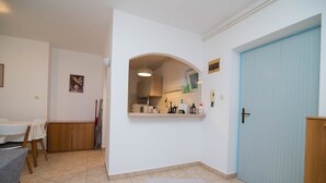 Un espacio habitable pequeño con comedor, kitchenette y una puerta azul.