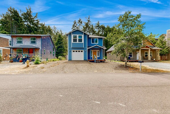 A residential area with two houses, one with a garage and a porch, and another with a front yard and a small tree. - Open concept Home with Deck Fire pit WIFI and Near Trails and Beach (Rockaway Beach)