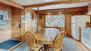 A wooden cabin with a dining table and chairs, a refrigerator, and a stove.