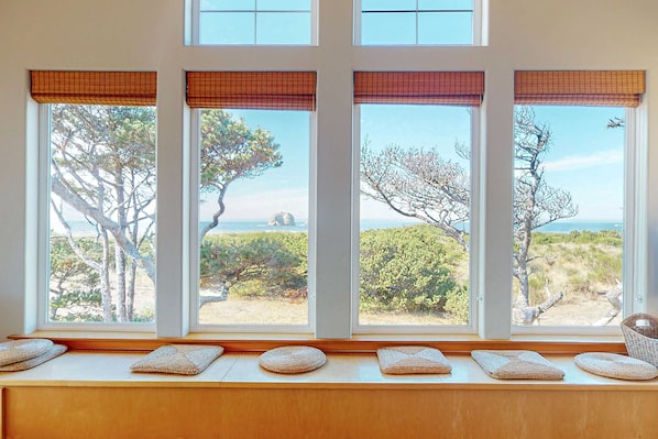 A room with four windows, each with a view of the beach and trees. - Beachfront home with private beach access fireplace washer dryer yard deck (Rockaway Beach)