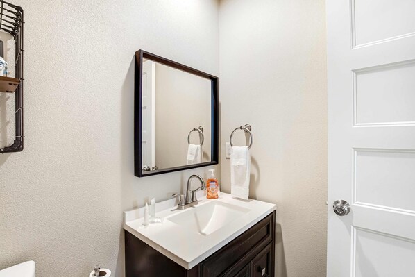 Une salle de bain avec un lavabo blanc, un miroir et un porte-serviettes.