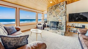 Una sala de estar con chimenea de piedra, televisor y estantería.