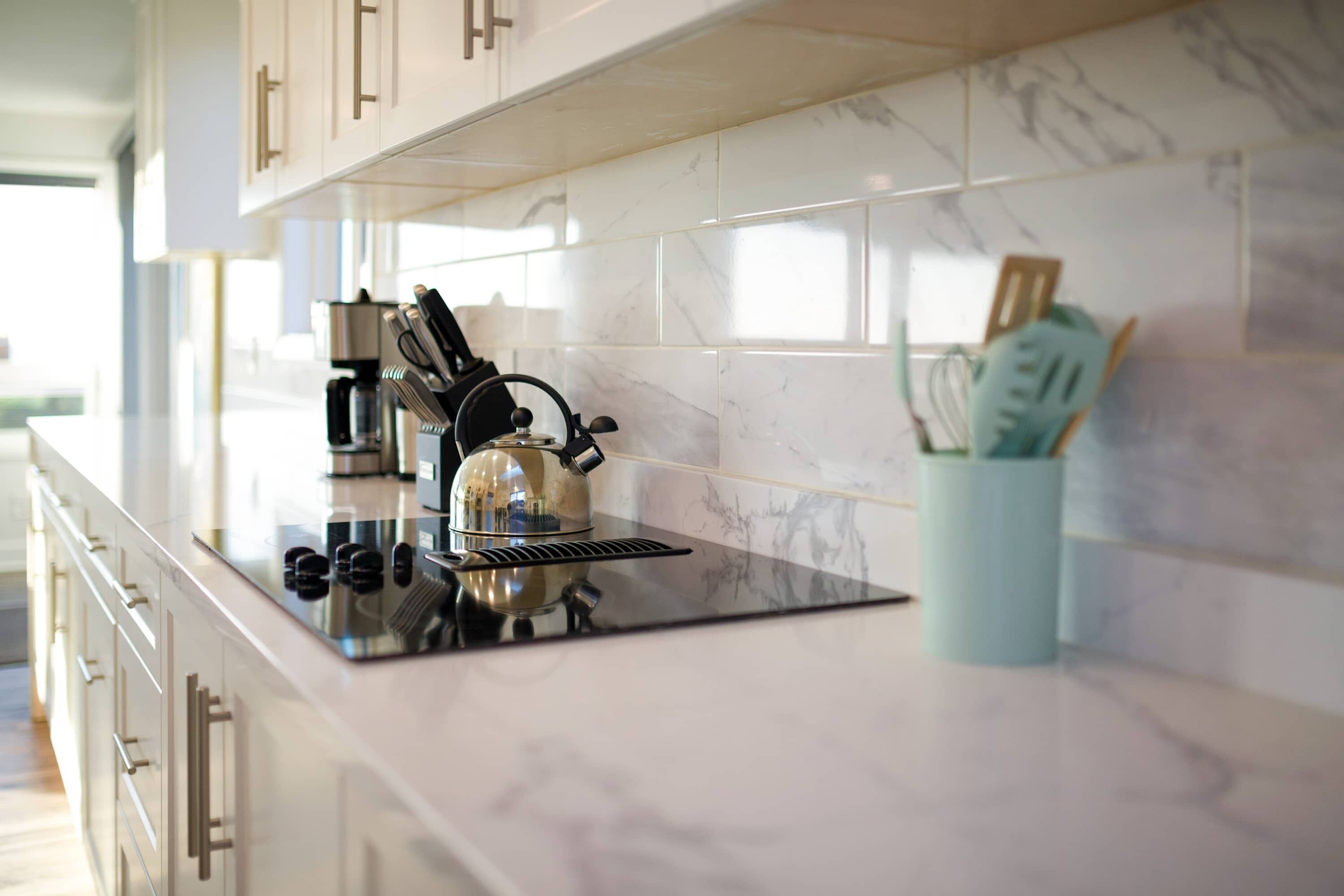 A modern kitchen with a black induction cooktop, a kettle, and a coffee maker.