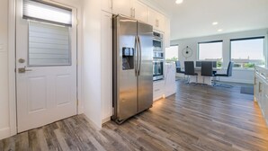 Una cocina moderna con un refrigerador de acero inoxidable, horno empotrado y un comedor con mesa y sillas.