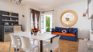Eine moderne Küche mit Esstisch, Stühlen und einem blauen Sofa mit orangefarbenem Kissen.