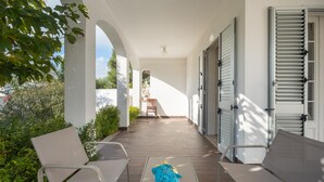 Ein überdachter Außenbereich mit Tisch, Stühlen und einer Statue.