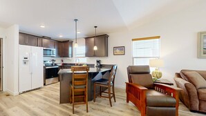 A modern kitchen with a central island, wooden chairs, a sofa, and a dining table. - Indulge in Ocean Bliss Where Elegance Meets Ocean Breeze (Rockaway Beach)