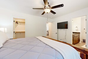 Une chambre avec un lit, un ventilateur de plafond, une télévision et un coin cuisine.