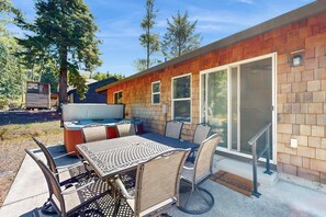 Un espace extérieur aménagé en terrasse, avec une table et des chaises en métal, un jacuzzi et une plateforme en bois.