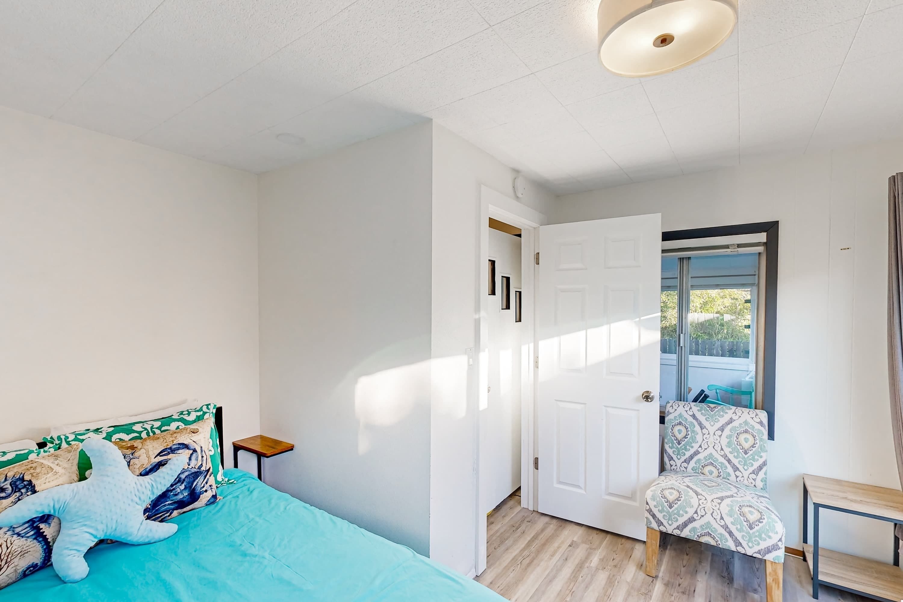 Une chambre à coucher comprenant un lit, une chaise, une petite table et une porte donnant sur un balcon.