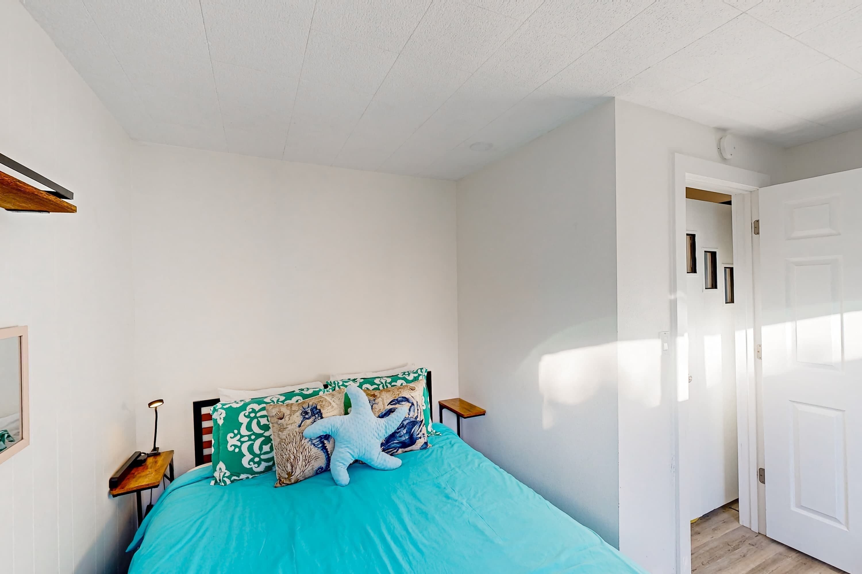 Une chambre à coucher avec un lit, des oreillers, une table de chevet et une porte.