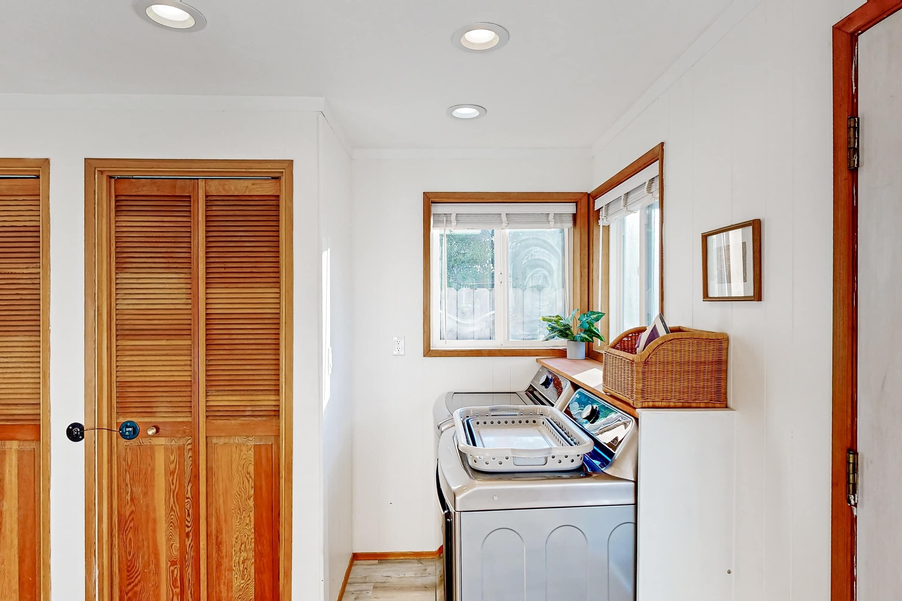 A laundry area with a washing machine, dryer, and wooden doors.