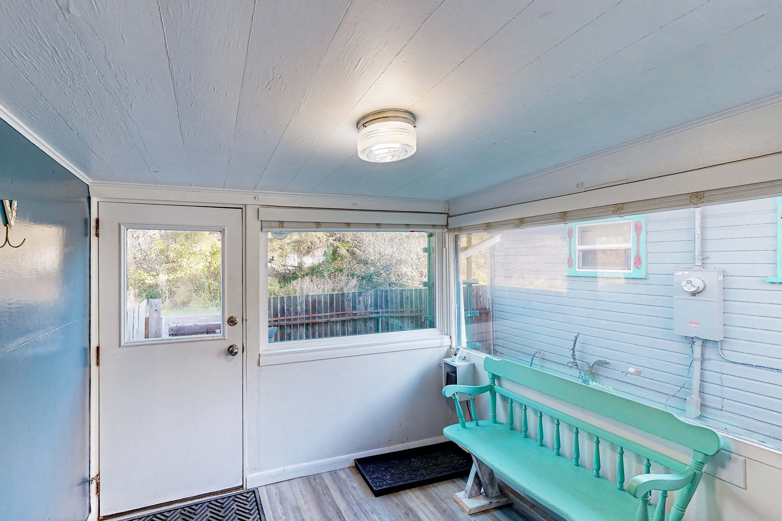 A room with a door, a window, a bench, and a ceiling light fixture.