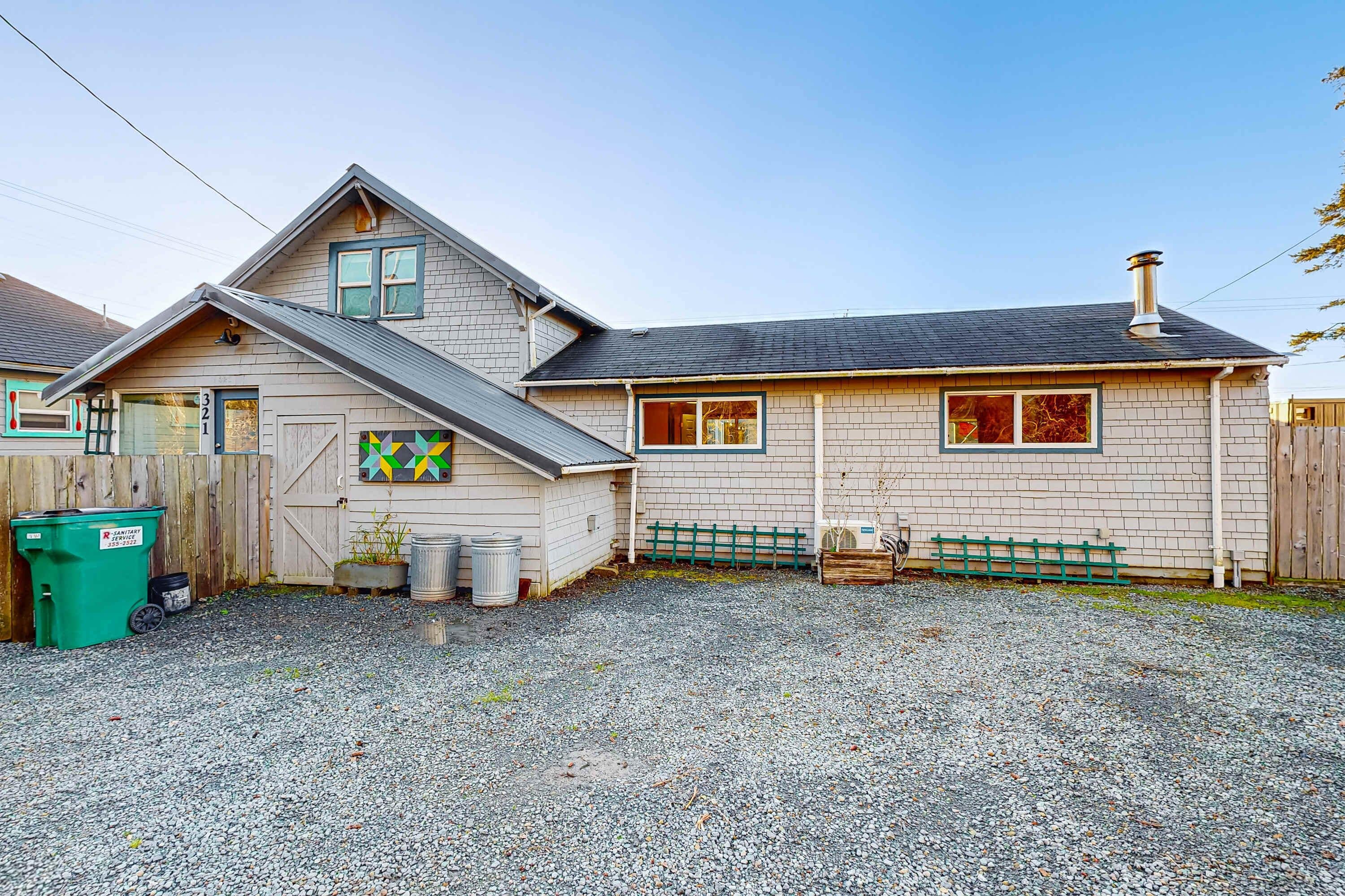 A two-story house with a gravel driveway and a wooden fence.