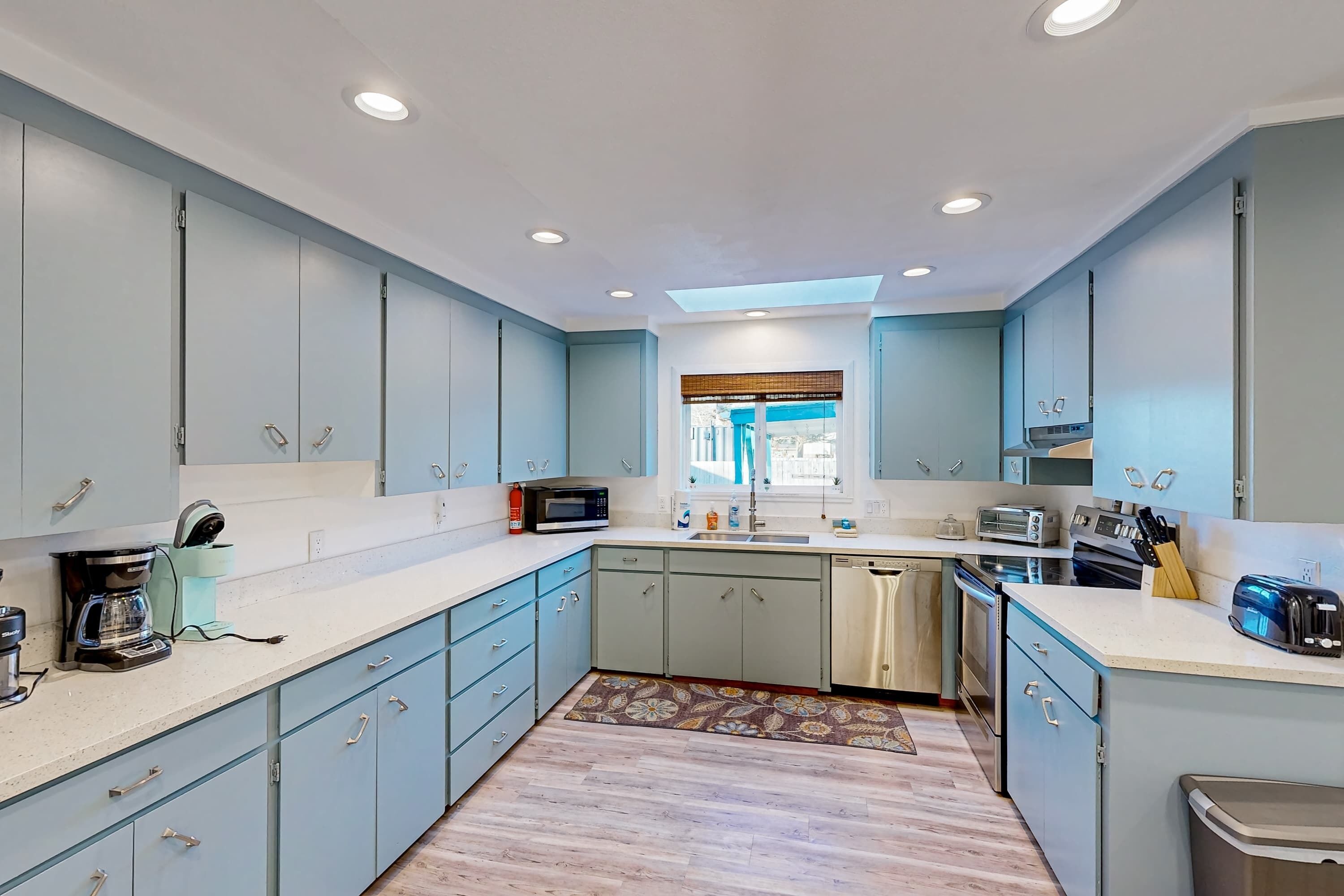 Una cocina moderna con armarios azul claro, una isla central y un ventanal con vistas.