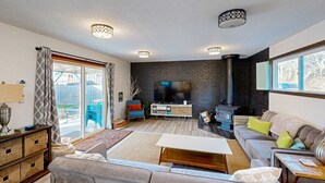 Ein modernes Wohnzimmer mit einer Couch, einem Couchtisch und einem Fernseher. Ein Kamin, ein Fenster und eine Ziegelwand sind ebenfalls vorhanden.