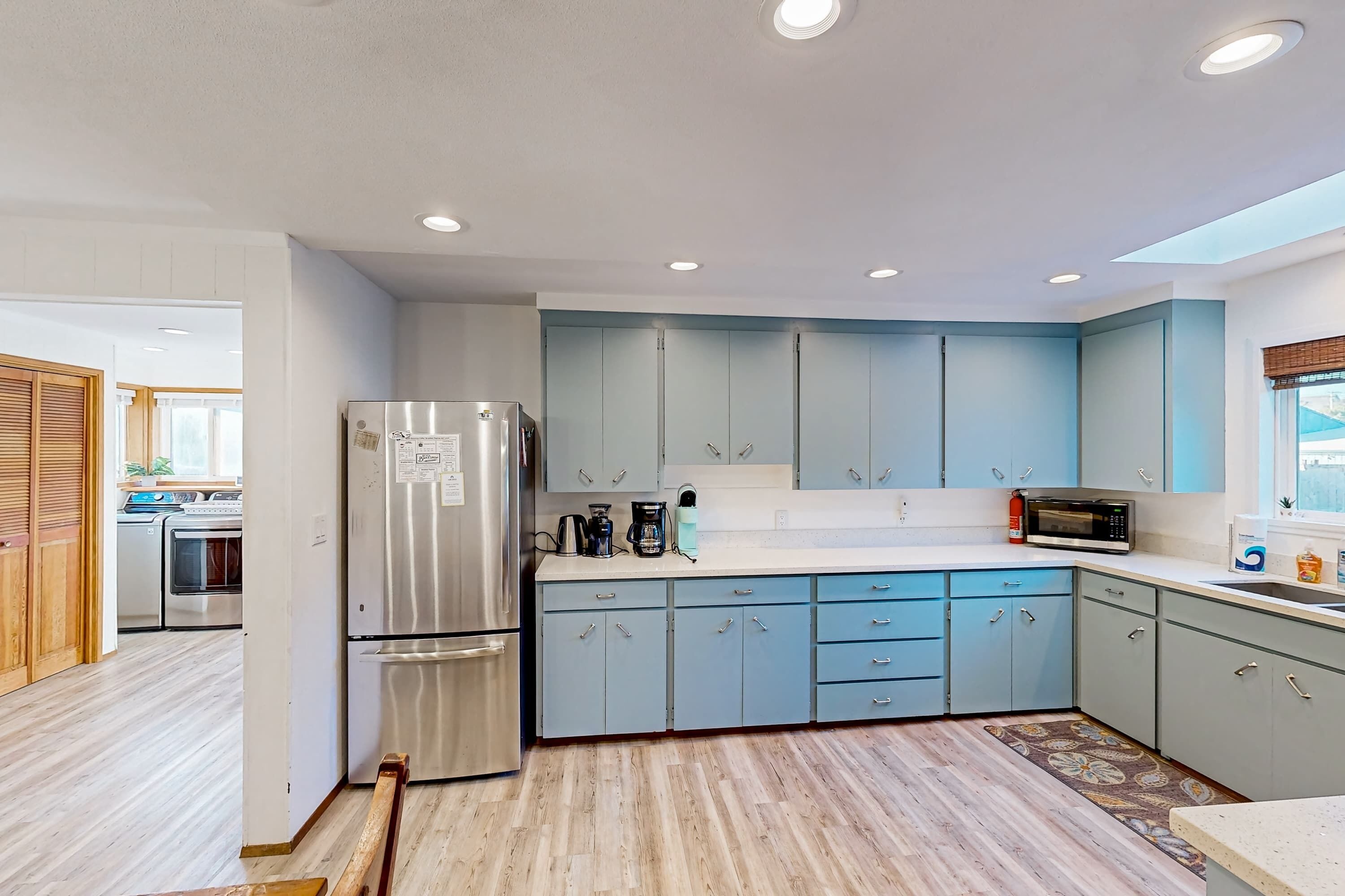 Una cucina moderna con mobili azzurri, elettrodomestici in acciaio inossidabile e pavimento in legno.