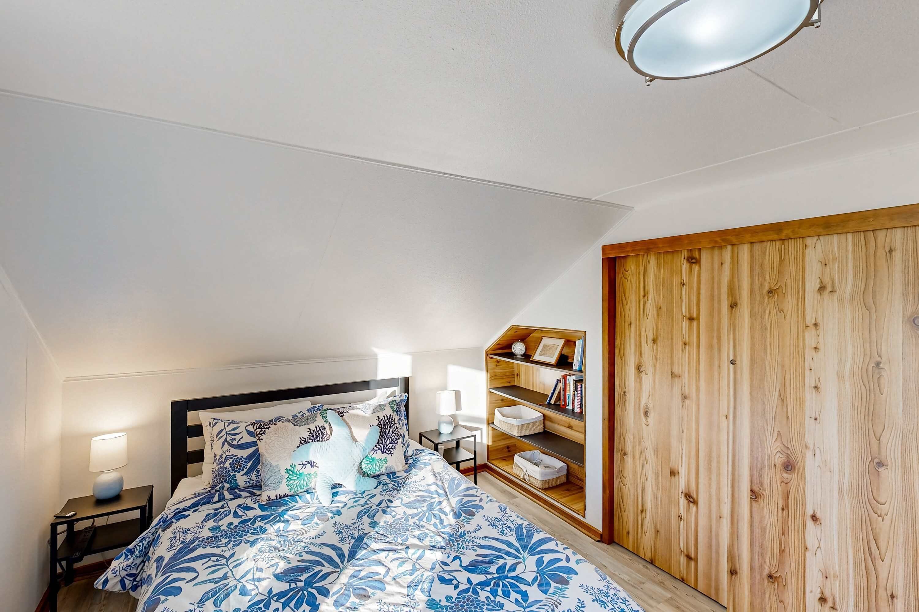 Ein Schlafzimmer mit einem Bett, Nachttischen, einem Holzschrank und einer Regalwand.