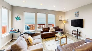 A living room with a large window, a flat-screen TV, and a wooden coffee table. - Spacious retreat with beautiful ocean views dog friendly with WiFi patio (Rockaway Beach)