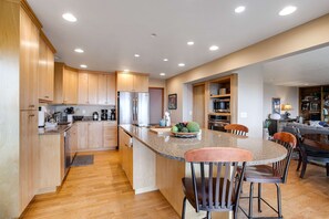 A modern kitchen with wooden cabinets, a granite countertop, and a central island with bar stools. - Exquisite Home with Top of the World Views Free WiFi Washer Dryer (Tillamook)