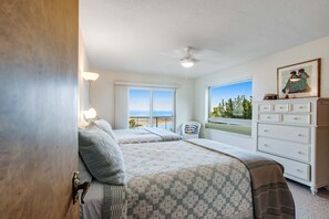 A bedroom with two beds, a dresser, a chair, and a window with a view of the ocean. - Exquisite Home with Top of the World Views Free WiFi Washer Dryer (Tillamook)