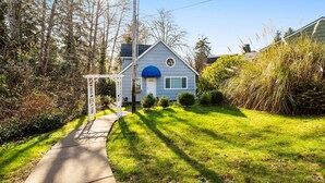 A residential house with a covered porch, a clear sky, and a well-maintained lawn. - Two story getaway with a washer dryer central AC and WiFi dogs welcome (Tillamook)