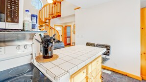 A kitchen with a microwave, stove, and a wooden staircase leading to another room. - Two story getaway with a washer dryer central AC and WiFi dogs welcome (Tillamook)