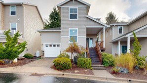 A row of townhouses with a central building featuring a front porch, a garage, and a staircase leading to the second floor. - Modern Ocean Highlands home with Netarts Bay and ocean views fireplace dogs OK (Tillamook)