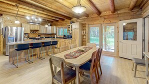 L’intérieur d’une cabane en bois comprend une cuisine, un coin repas et de grandes fenêtres.