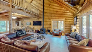 L’intérieur d’une cabane en rondins, avec une cheminée, des canapés en cuir et une tête d’élan fixée au mur.
