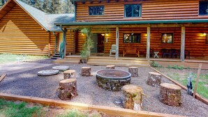 Une cabane en rondins avec un porche, un espace salon extérieur et un foyer.