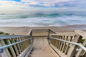 Un escalier en bois menant à une plage d’où l’on a une vue sur l’océan.