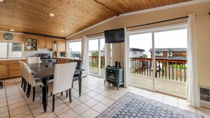 A spacious kitchen with wooden ceiling, large windows, and a dining area. - Ocean View Home with Rec Room Rock Wall and Private Hot Tub A Block From Beach (Rockaway Beach)