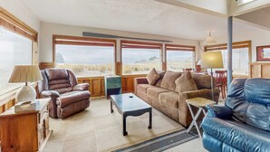 Un salon spacieux, doté de canapés en cuir, d’une table basse et de grandes fenêtres offrant une vue sur le paysage désertique.