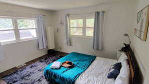 A bedroom with a bed, a window, a radiator, and a wall-mounted lamp.