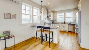 Una cocina moderna con una isla central, luces colgantes y vistas a la ciudad.
