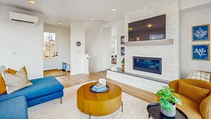 Una sala moderna con un sofá azul, una mesa de centro redonda de madera y una chimenea.